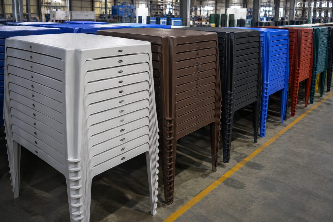 Stacked moulded plastic tables in white, brown, black, blue, red and green